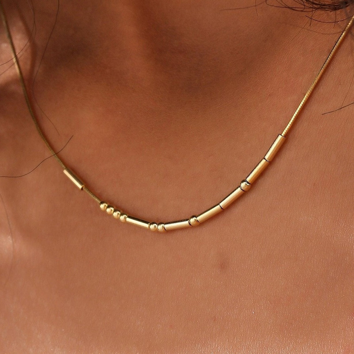 Gold Morse code necklace worn on the neckline