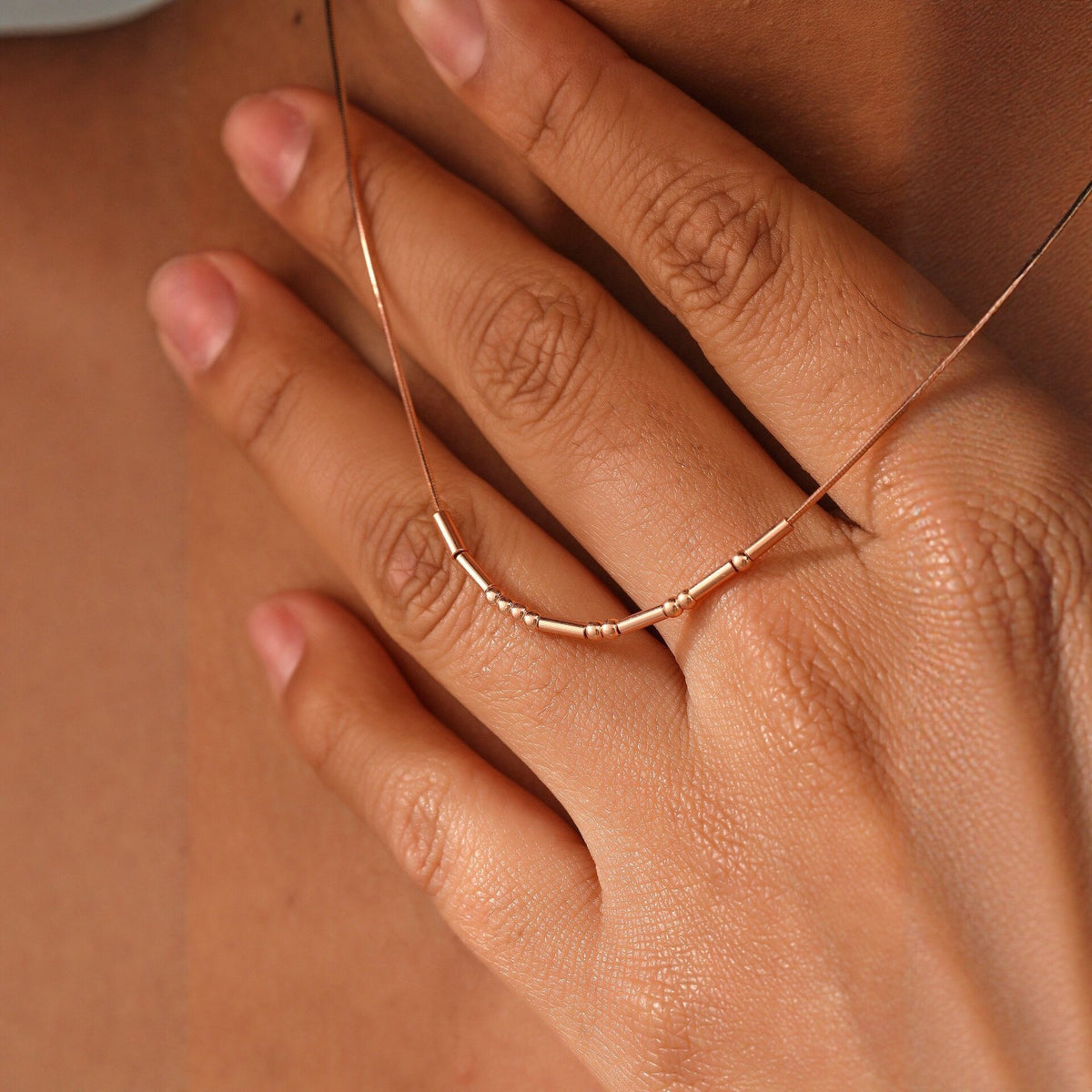 Rose gold Morse code necklace in hand